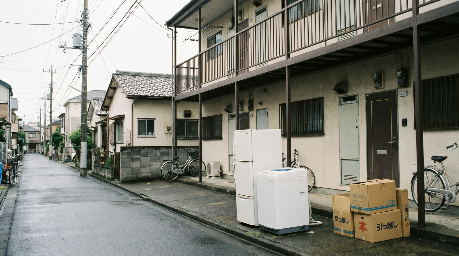 A refrigerator and washing machine on the pavement outside a Japanese apartment building on moving day